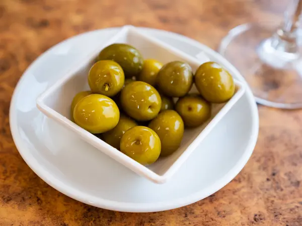 stock image Appetites are waiting on table, light snack - bowl with pickled green olives. Traditional vegetable addition to main dishes, snacks and alcoholic beverages