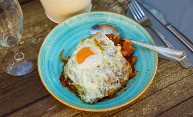 Rich cod stew with mix of vegetables in garlic and tomato salsa, topped with fried egg, served on rustic wooden table. Traditional recipe from Basque Country cuisine clipart