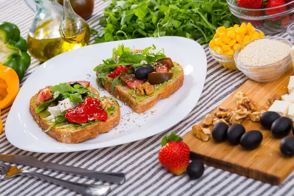 stock image Healthy toasts with guacamole and vegetables served on white plate on background with fresh ingredients