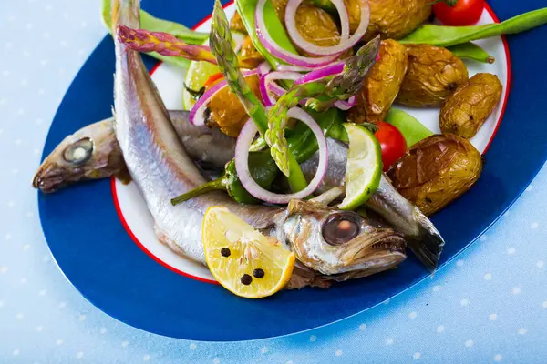 stock image Delicious poutassou stewed in white wine with side dish of baked potatoes and fresh snap peas