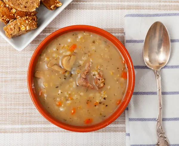 stock image Hearty homemade soup with forest mushrooms, pork, vegetables and pearl barley. Russian cuisine