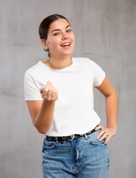 Stock image Photo of flirty young woman standing posing intriguingly against gray shadeless background