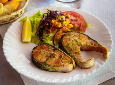 Healthy eating. Grilled steaks of salmon served with vitamin vegetable salad and slice of lemon clipart