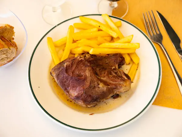 stock image Delicious fried pork cheeks served in sauce with baked potatoes on plate