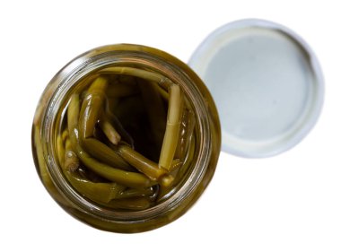 Open glass jar filled with pickled green ramsons scapes with mild garlic flavor, showcasing traditional tangy and crunchy appetizer of Eastern European cuisine. Isolated over white background clipart