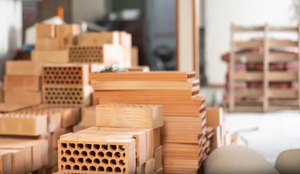 stock image Closeup of stack of red bricks inside building under construction. Building materials prepared for work..