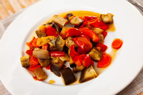 Stock image Saute of chopped baked eggplant, bell pepper, tomato, carrots with pork bacon pieces on plate. Tasty homemade dinner