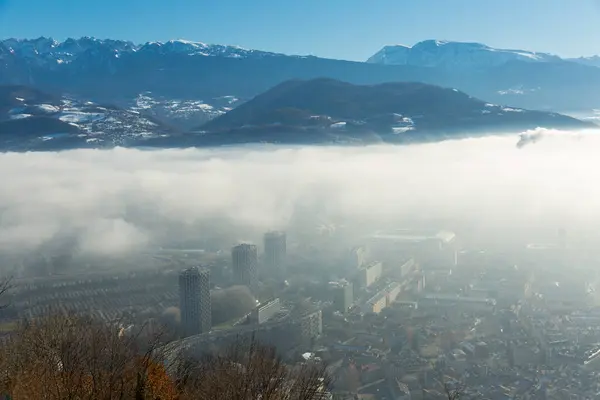 stock image Picturesque mountains landscape of snowy Alps and downtown of Grenoble under clouds in sunny winter day