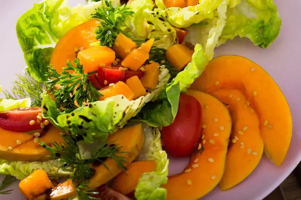 stock image .Baked pumpkin salad. Put on a plate lettuce, pumpkin, cherry tomatoes, sesame. Season with olive oil sauce, salt, pepper, lemon and pumpkin puree.