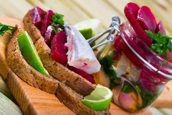 stock image Blue whiting of home salt pickling in marinade of lime juice and olive oil with beets and greens served on rye bread