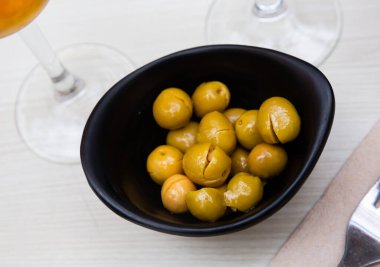 Pickled olives with a stone - a typical Spanish tapas in a black plate..... clipart