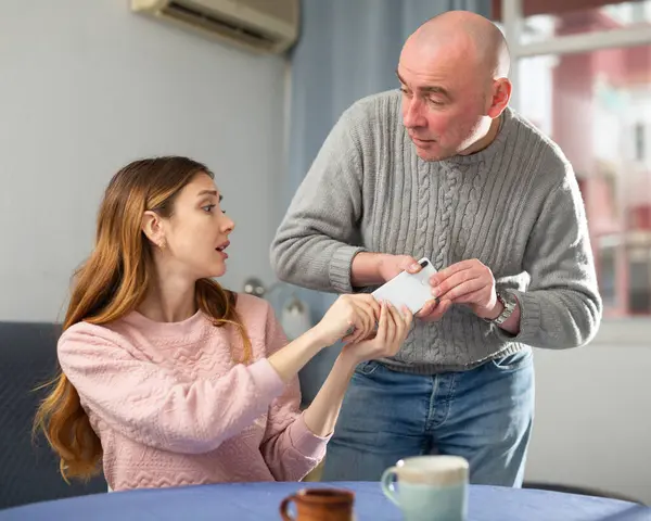 stock image Emotional man swearing at young wife takes her mobile phone out of her hands