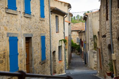 Medieval old houses with blue shutters on narrow street of French town Lagrasse clipart