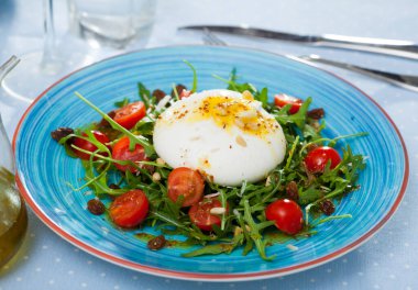 Healthy salad with Italian cheese burrata, greens, tomatoes, raisins and pine nuts clipart