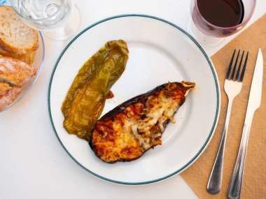 Plate of a delicious dish of baked stuffed eggplant with cheese rubbed on top clipart