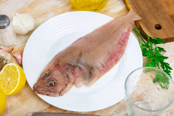 stock image Raw megrim fish served on plate with parsley and fresh lemon