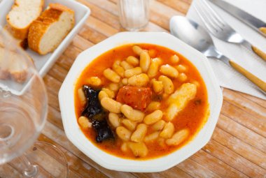 Popular delicious dish of Spanish cuisine is Fabada soup, made from white beans with smoked pork knuckle and Choriso and ..Morcilla sausage clipart