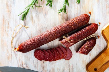 Fresh smoked russian sausage cut in slices on a wooden surface, close-up clipart