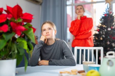 Portrait of young unhappy teenage girl ignoring her mother before celebrating New Year clipart