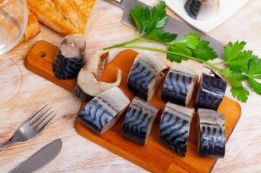 Image of slices of lightly salted mackerel fish served with greens on wooden desk clipart