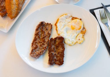 Fried egg with traditional Scottish Lorne sausage served on plate . clipart