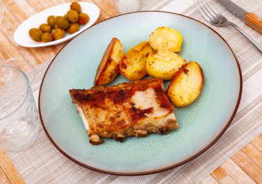 Delicious barbecued pork spare ribs served with baked potatoes on plate clipart