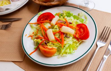 Tasty vegetable salad from fresh lettuce with tomato slices, red onion, grated carrot and pickled asparagus clipart