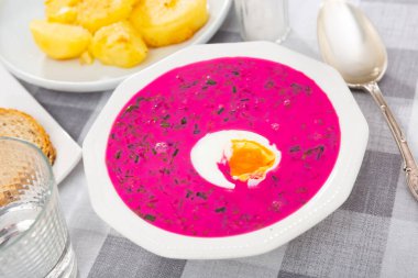 Popular dish of Belarusian cuisine is the summer vegetable soup Kholodnik, prepared on the basis of beetroot and decorated ..with sliced boiled egg on top clipart