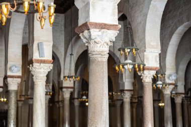 Close-up view of marble columns with ornately carved capitals supporting vaulted ceiling of prayer hall in Great Mosque of Kairouan, showcasing traditional historical Islamic architecture clipart