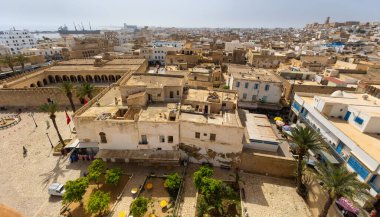 City panorama unfolding from heights of Ribat tower in Sousse, featuring ancient Great Mosque, active port on Mediterranean Sea and tightly packed residential areas under clear sky of Tunisia. clipart