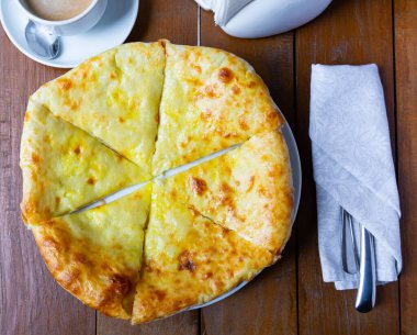 Upper view of freshly baked Imeretian khachapuri on wooden table. Traditional Georgian flatbread topped with sulguni cheese clipart