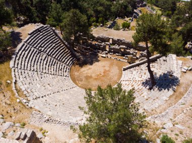 Aerial view of remains of Roman theater in ancient Lycian city of Arycanda located on mountain slope overgrown with green coniferous trees on summer day, Antalya province, Turkey clipart