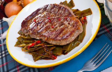 Delicious fried beef entrecote served with vegetable garnish of stewed green beans and pepper clipart