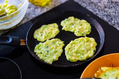 Cooking delicious zucchini pancakes in a frying pan clipart