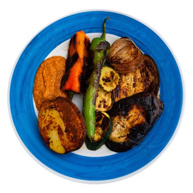 Appetizing grilled vegetables with potatoes and romesco sauce served on plate. Isolated over white background clipart