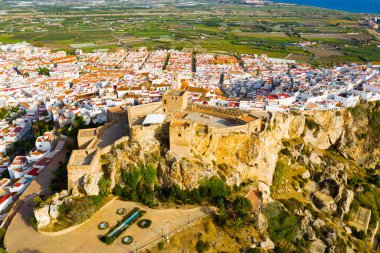 Picturesque autumn landscape with small Spanish town of Salobrena located on edge of stone cliff overlooking ancient fortified Arab castle.. clipart