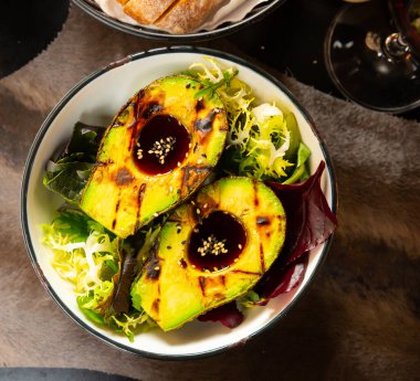 Grilled avocado with ponzu sauce served with mix of fresh greens, healthy food clipart