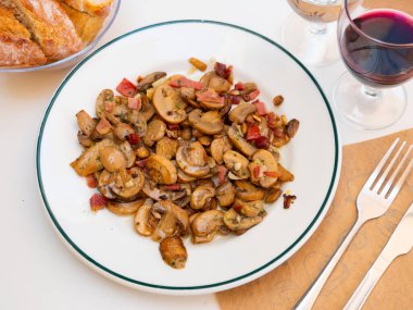 Sauteed Mushrooms served on white plate with glass of wine clipart