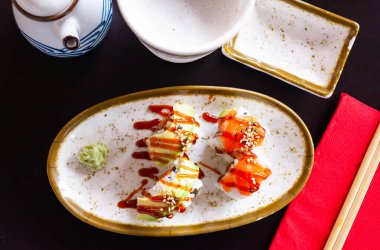 Traditional Japanese food appetizer - uramakizushi rolls with filling of raw salmon and avocado seasoned with unagi sauce and sesame seeds, served with with spicy wasabi and soy sauce clipart