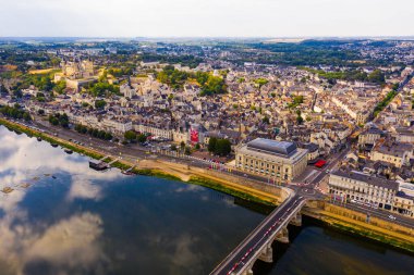 Drone view of summer cityscape of Saumur overlooking theatre Le Dome on bank of Loire River with medieval fortified Chateau on background, France clipart