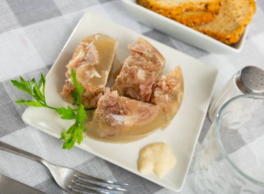 Traditional dish of Russian cuisine is a kholodets made from a jelly-like mass from cooling meat broth with pieces of meat. ..Served with sauce and garnished with a sprig of fresh parsley clipart