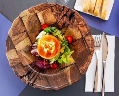 Traditional Spanish vegetable salad with mix of greens, tomatoes, grilled goat cheese medallion and nuts . clipart