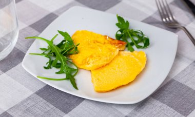 Tender and lush, slices of omelet are laid out on plate, decorated with rucola. Continental breakfast in restaurant. Light and hearty breakfast, healthy food, easily digestible protein clipart