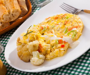 Tasty omelet with vegetables served with baked cauliflower and delicate cheese sauce.. clipart