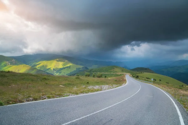 Dağda yol ve derin yağmurlu gökyüzü. Doğa manzarası.