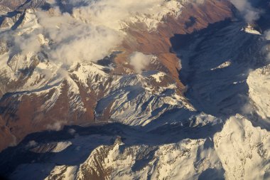 Dağ sırası ve gündüz mavi gökyüzünde beyaz bulutlar. Yukarıdan görünüm.