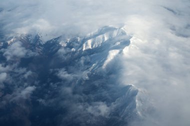 Dağ sırası ve gündüz mavi gökyüzünde beyaz bulutlar. Yukarıdan görünüm.