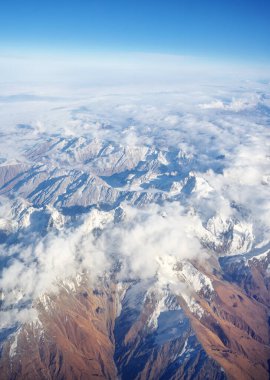 Dağ sırası ve gündüz mavi gökyüzünde beyaz bulutlar. Yukarıdan görünüm.