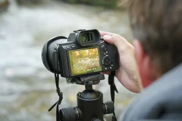 摄影记者在工作中手持数码相机 对风景拍照 自然与工作场所的人 图库图片