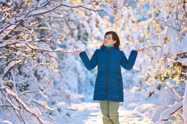 Genç kadın kar havasının tadını çıkarıyor. Güneşli bir kış gününde karla oynayan mutlu bir kadının portresi..